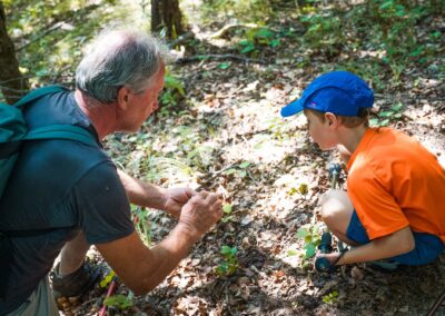 Una guida e un bambino osservano il suolo del bosco