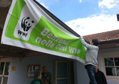 Un volontario appende lo striscione Benvenuti nelle Oasi WWF, nel 2013
